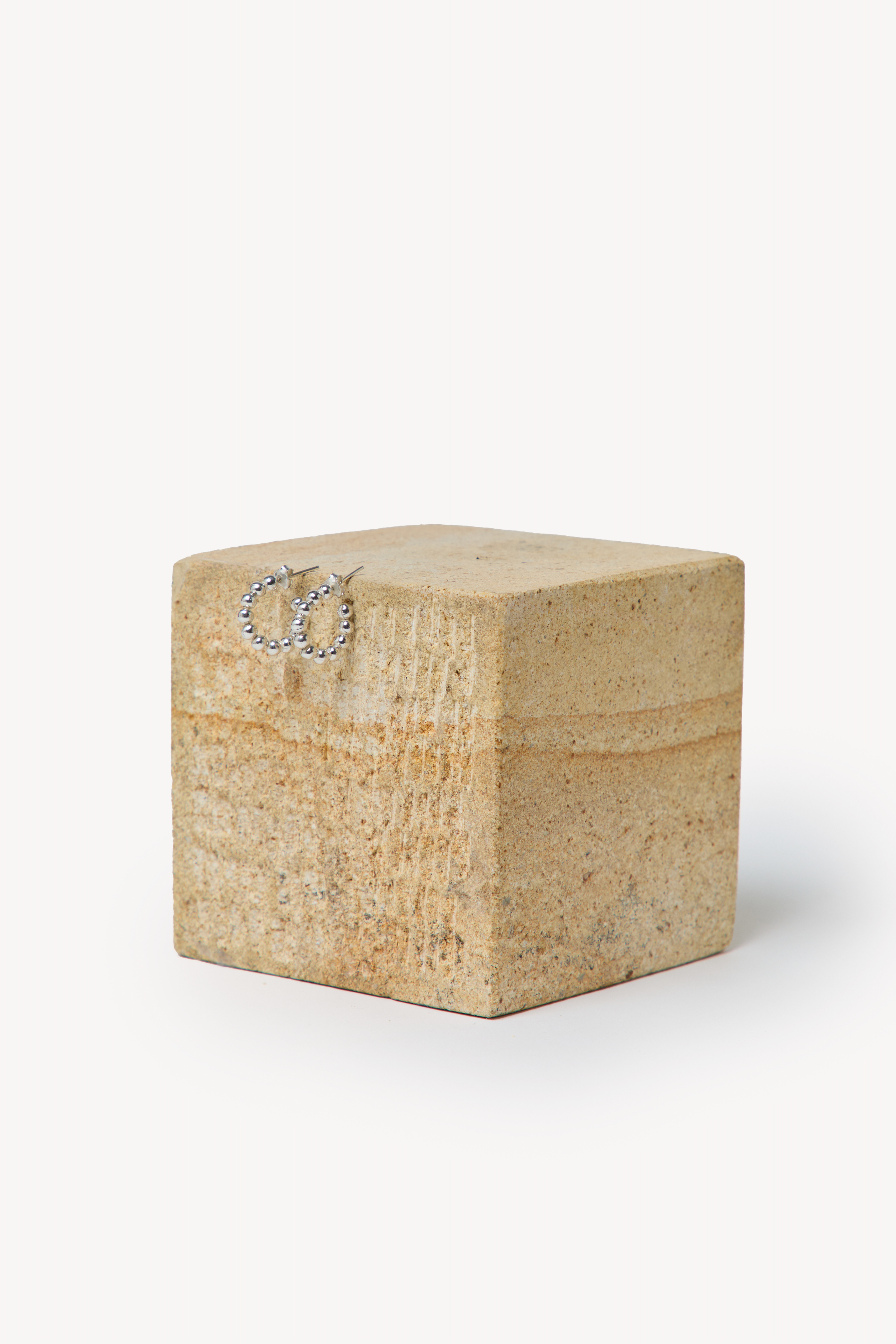 Handmade earrings placed on a box with a neutral background