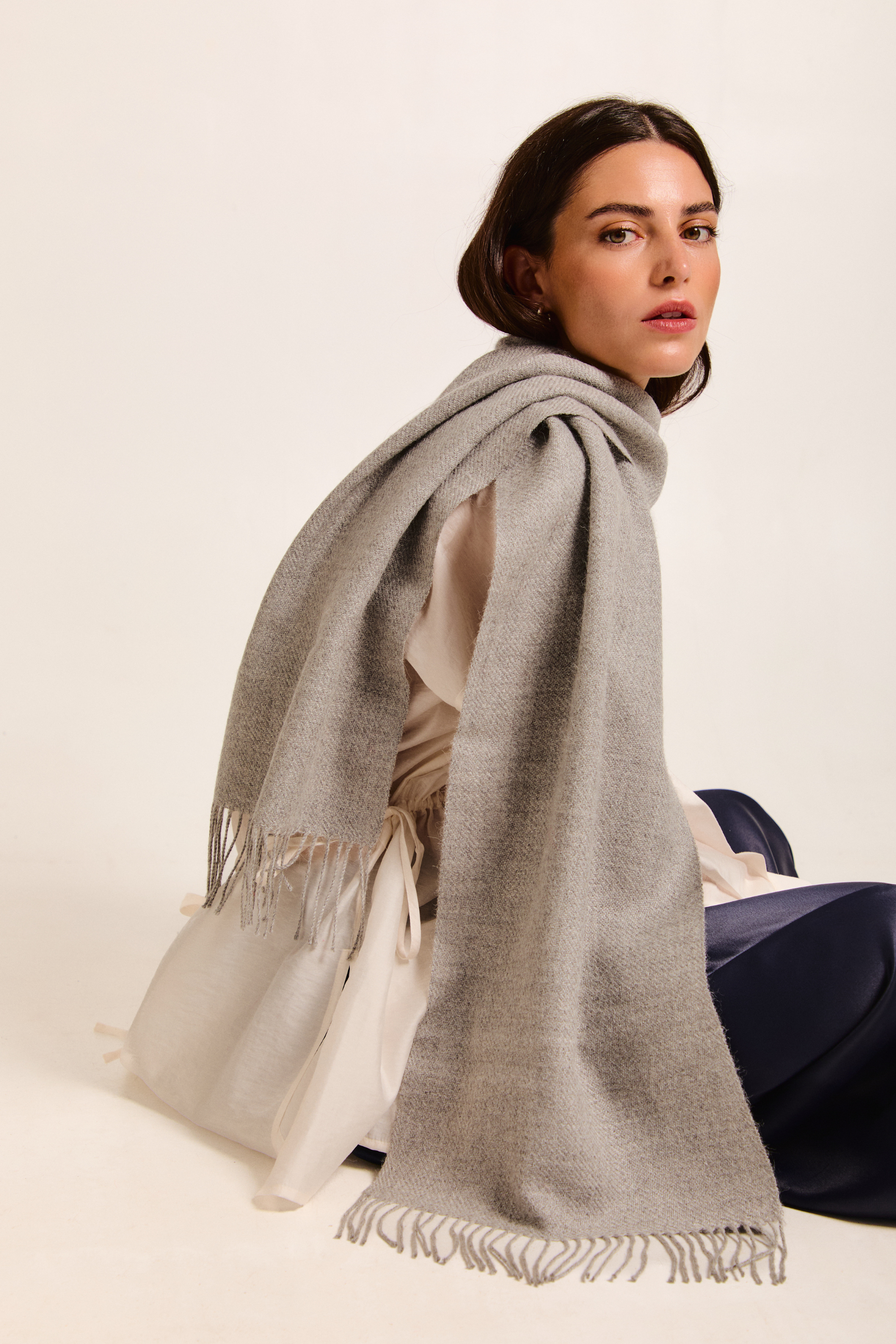 Model sitting with a handmade scarf on a neutral background.