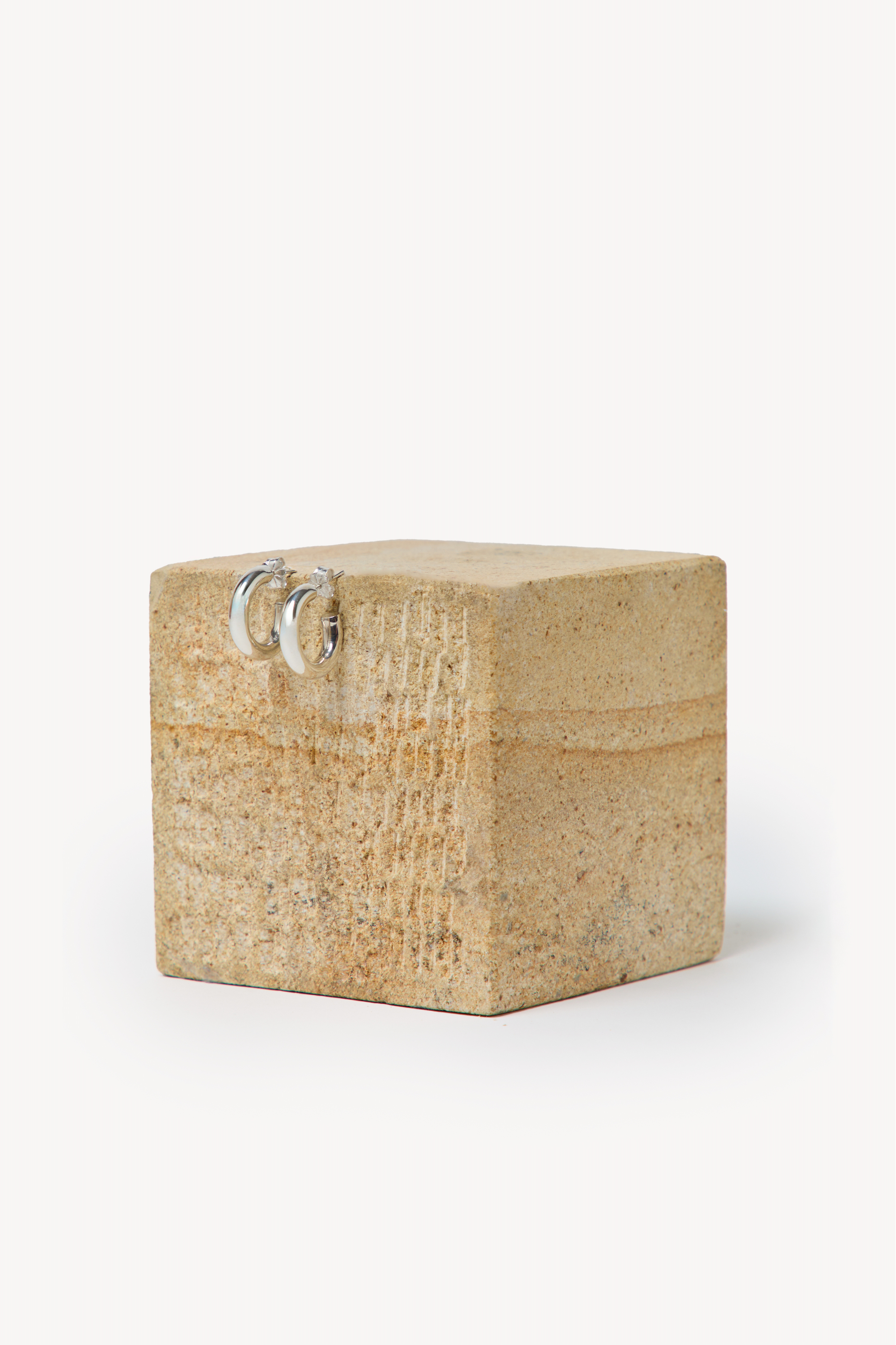 Handmade earrings placed on a box with a neutral background