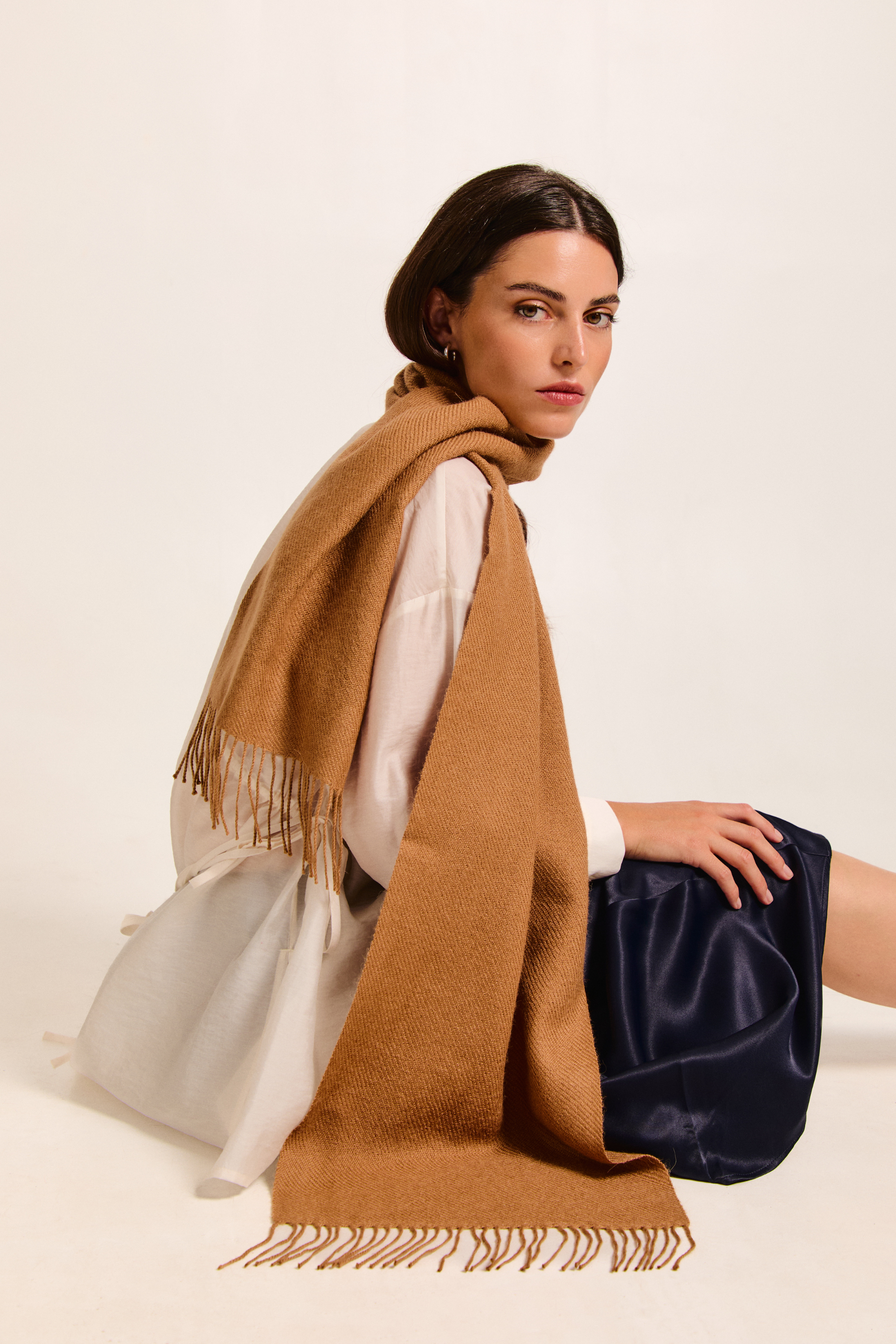 Model sitting with a brown handmade scarf on a neutral background.